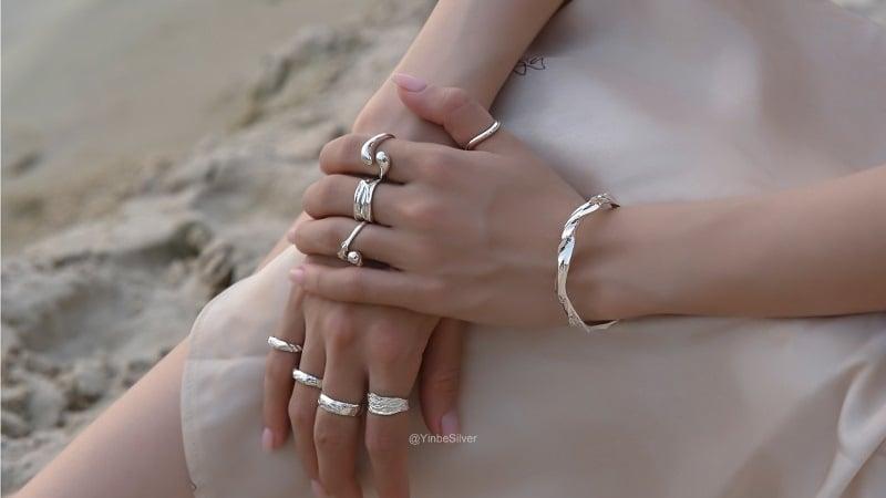 Nhẫn xương voi và phong thủy: Hình ảnh một bàn tay đeo nhẫn xương voi đặt trên một cuốn sách về phong thủy, thể hiện sự kết hợp giữa trang sức và kiến thức phong thủy.
